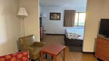 Habitación de hotel con cama, escritorio, silla, televisor y cómoda.