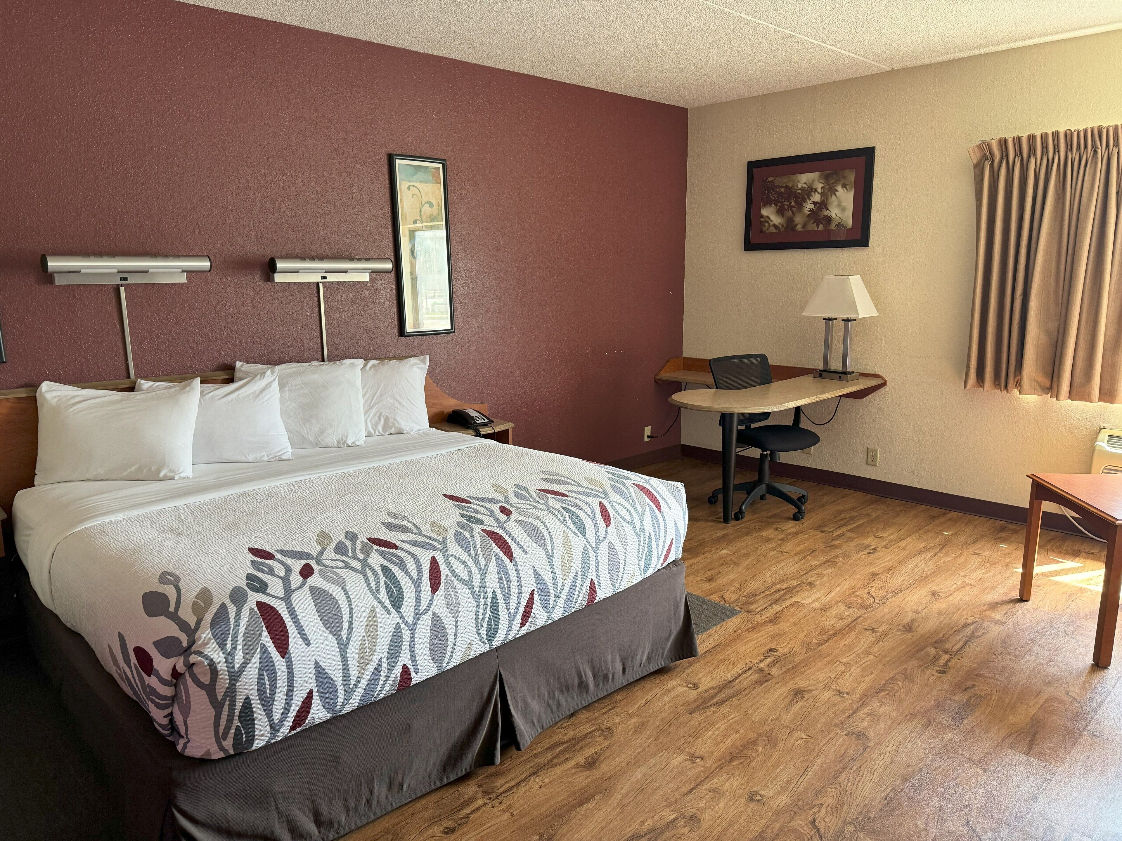 A hotel room with a bed, a desk, and a chair.