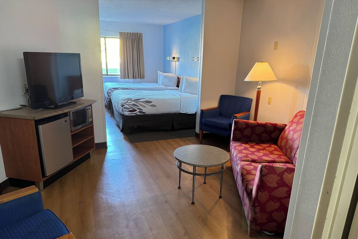 Habitación de hotel con cama, televisión, escritorio, silla, sofá y lámpara.