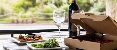 A table with a bottle of wine, a glass, and a pizza box.