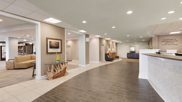 A spacious lobby with a reception desk, seating area, and a framed picture on the wall.