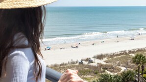 A beach view with a person in the foreground, a sandy beach, and the ocean.