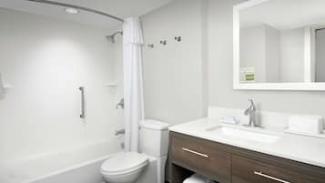 Un baño moderno con bañera, inodoro y tocador con espejo.