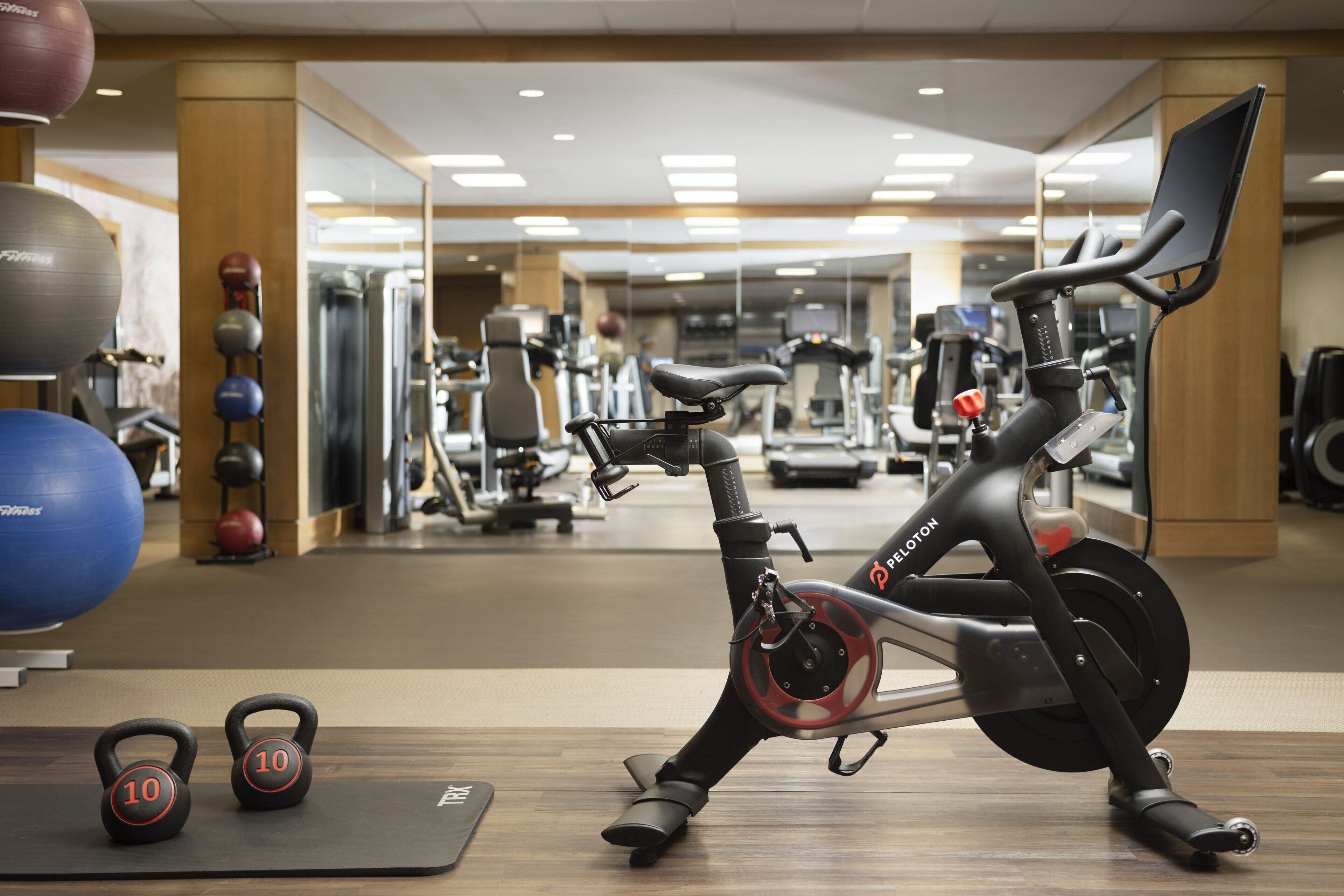 A stationary bike in a gym with kettlebells and exercise balls.
