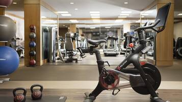 Een stilstandfiets in een sportschool met kettlebells en elastiekballen.