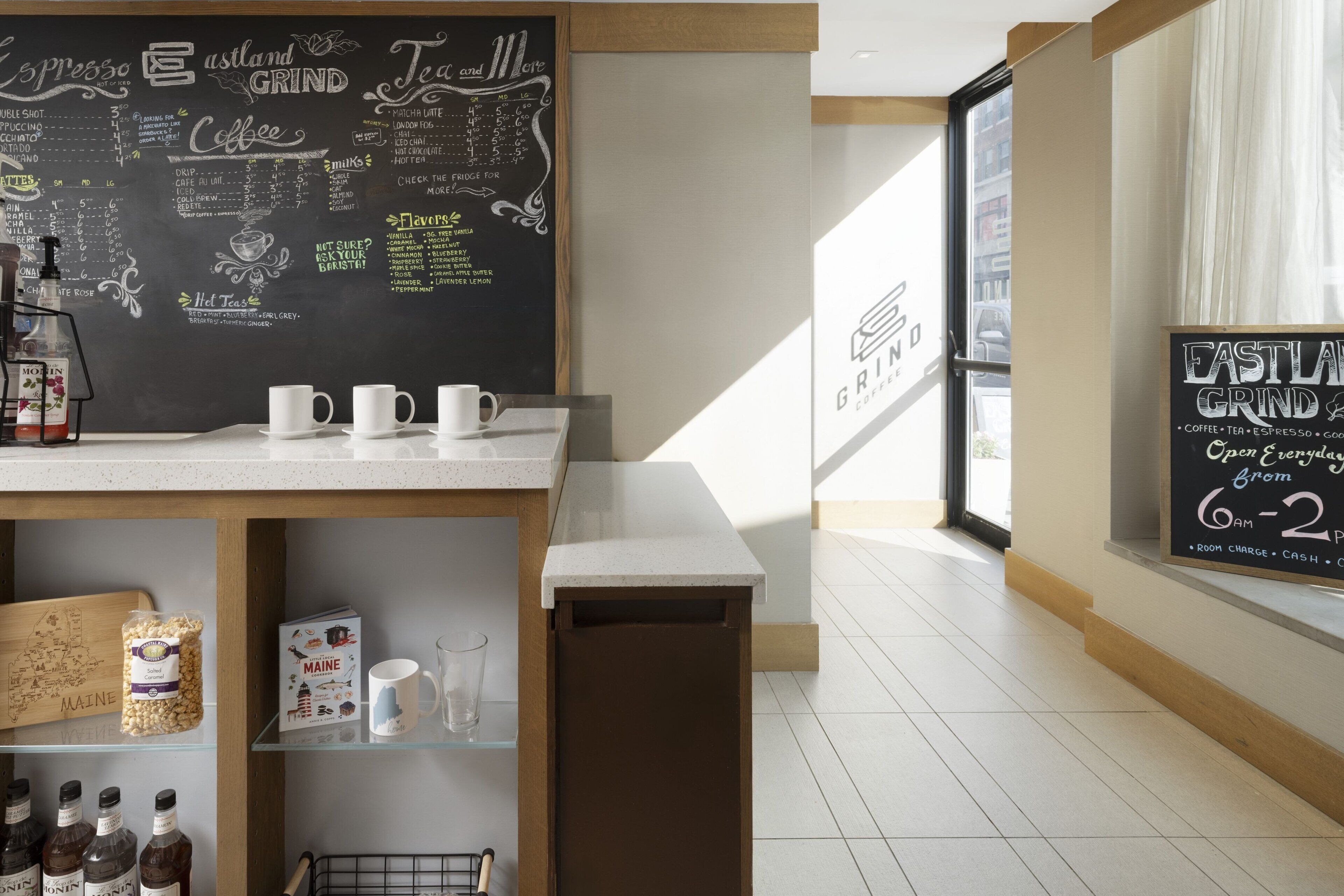 A coffee shop interior with a chalkboard menu, coffee brewing equipment, and a window with a view of the street.