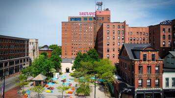 A cityscape with a prominent red-brick building labeled "EASTLAND" and a plaza with colorful seating and trees.