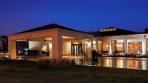 L’entrée d’un hôtel, dotée d’un espace d’attente abrité, d’une piscine et d’une façade bien éclairée.
