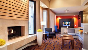 Un hall d’hôtel moderne doté d’une cheminée, d’un espace salon et d’un écran de télévision.