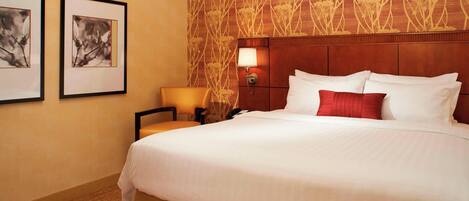 A hotel room with a large bed, a nightstand with a lamp, and two framed pictures on the wall.