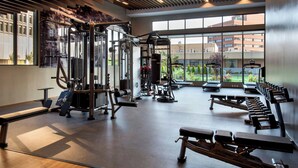 A gym with various exercise equipment, large windows, and a view of buildings outside. - Marriott Springfield Downtown (Springfield)