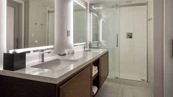A modern bathroom with a double sink vanity, a large mirror, and a glass-enclosed shower.