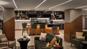 A modern hotel lobby with a bar area, seating arrangements, and a staircase. - Marriott Springfield Downtown (Springfield)