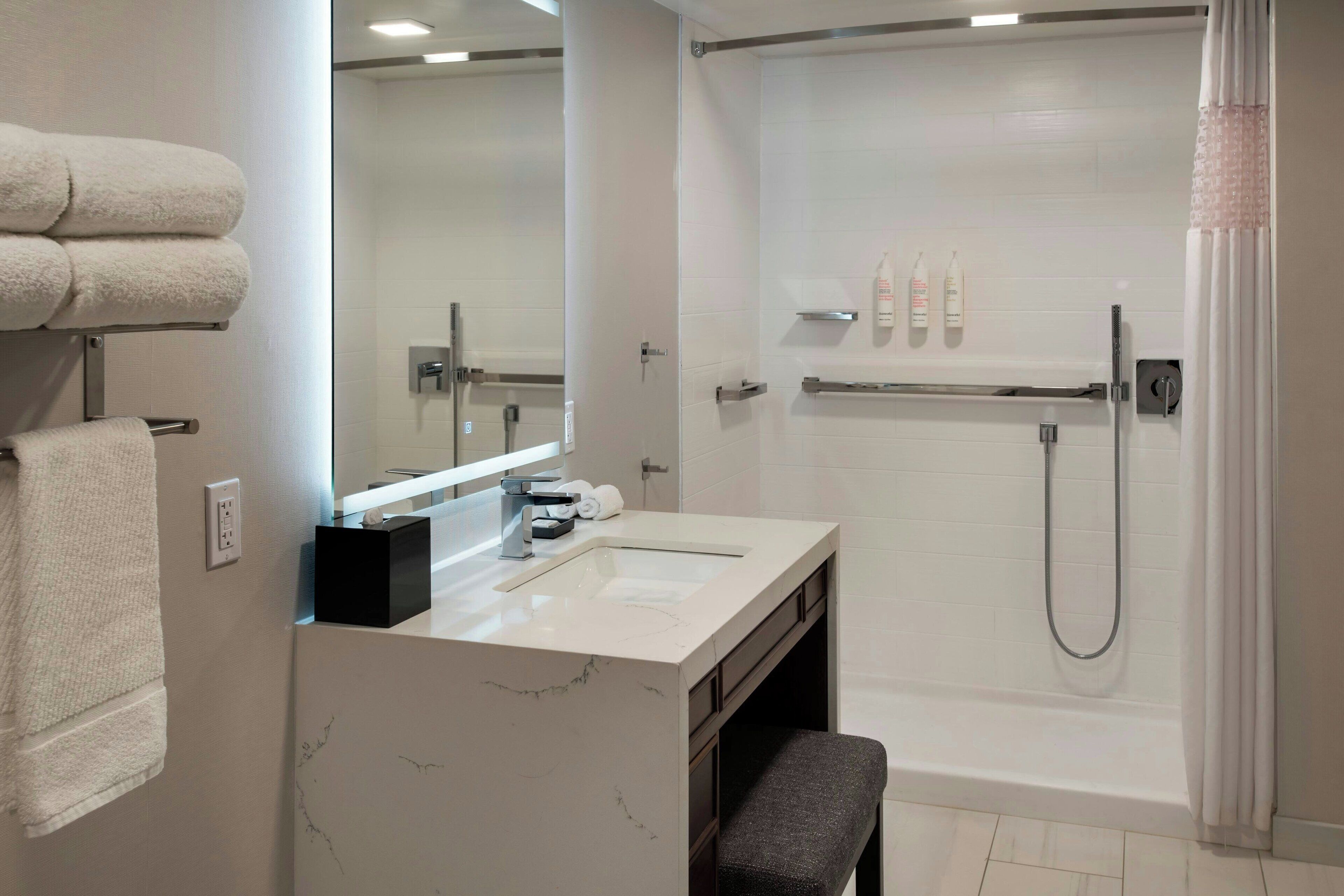 Un baño moderno con lavamanos de mármol, bañera y ducha.