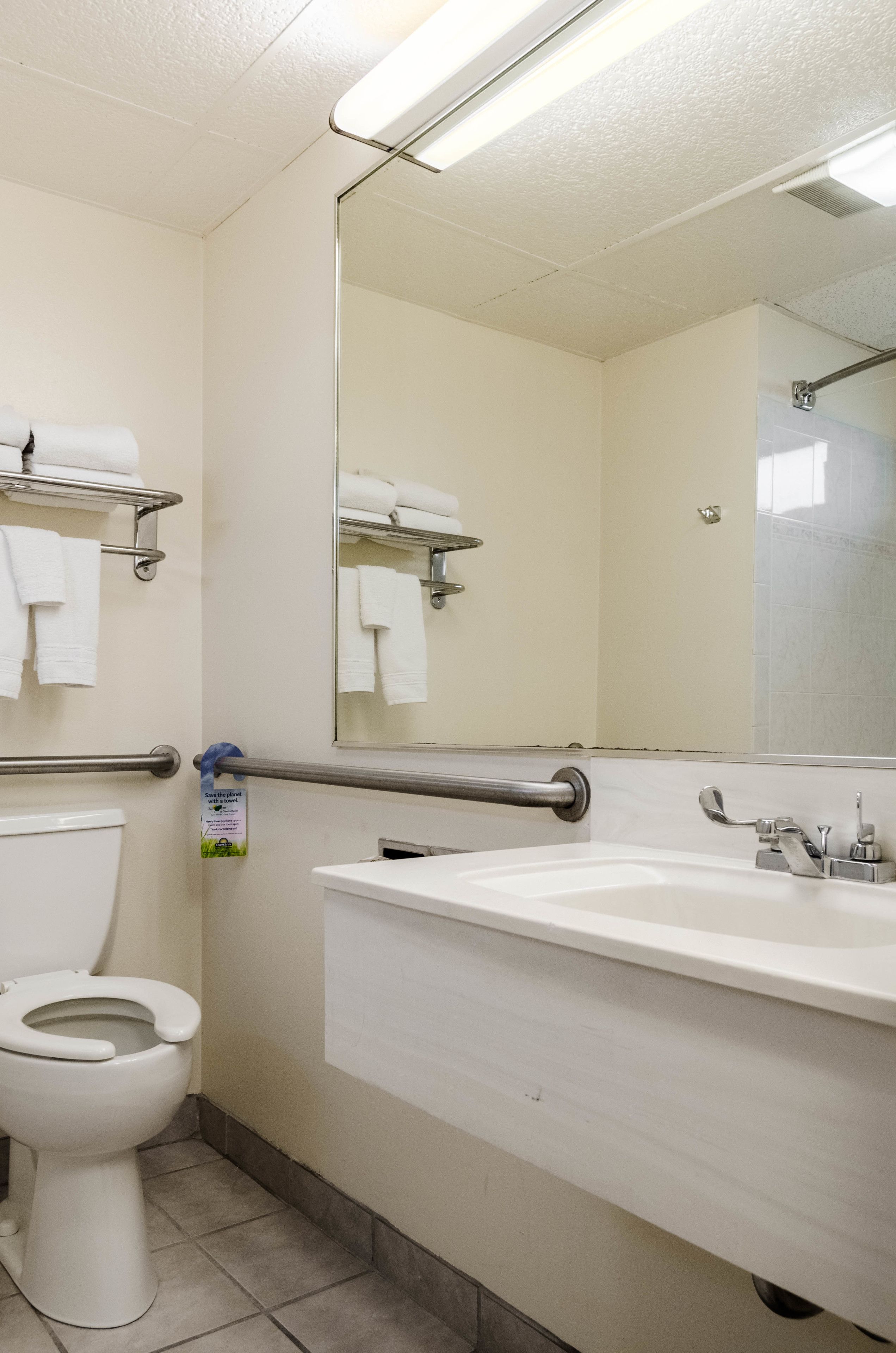 Un bagno con il water, un lavandino, uno specchio e porta asciugamani.