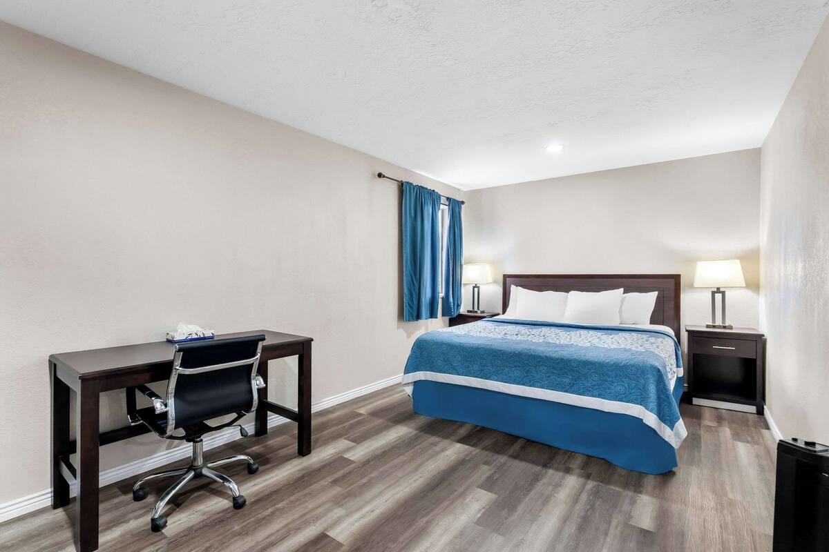 A hotel room with a bed, a desk, and a chair.