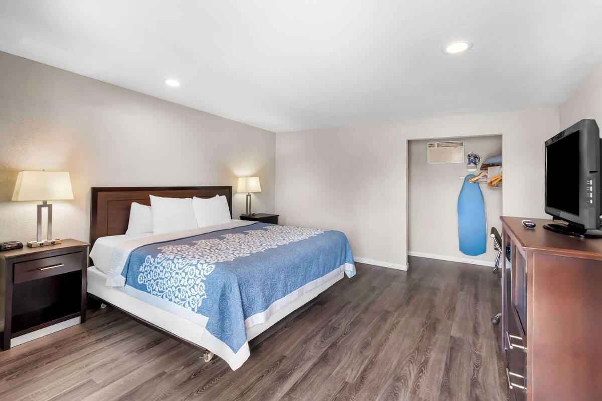 A hotel room with a bed, nightstands, a television, and a blue exercise ball against the wall.