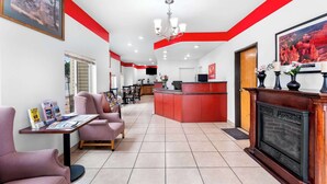 Een hotel lobby met een receptiebalie, een zithoek en een open haard.