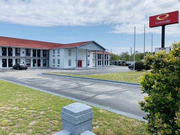 A two-story EconoLodge building with a red roof, a welcoming sign, and a parking lot. - Econo Lodge Crystal Coast (Morehead City)
