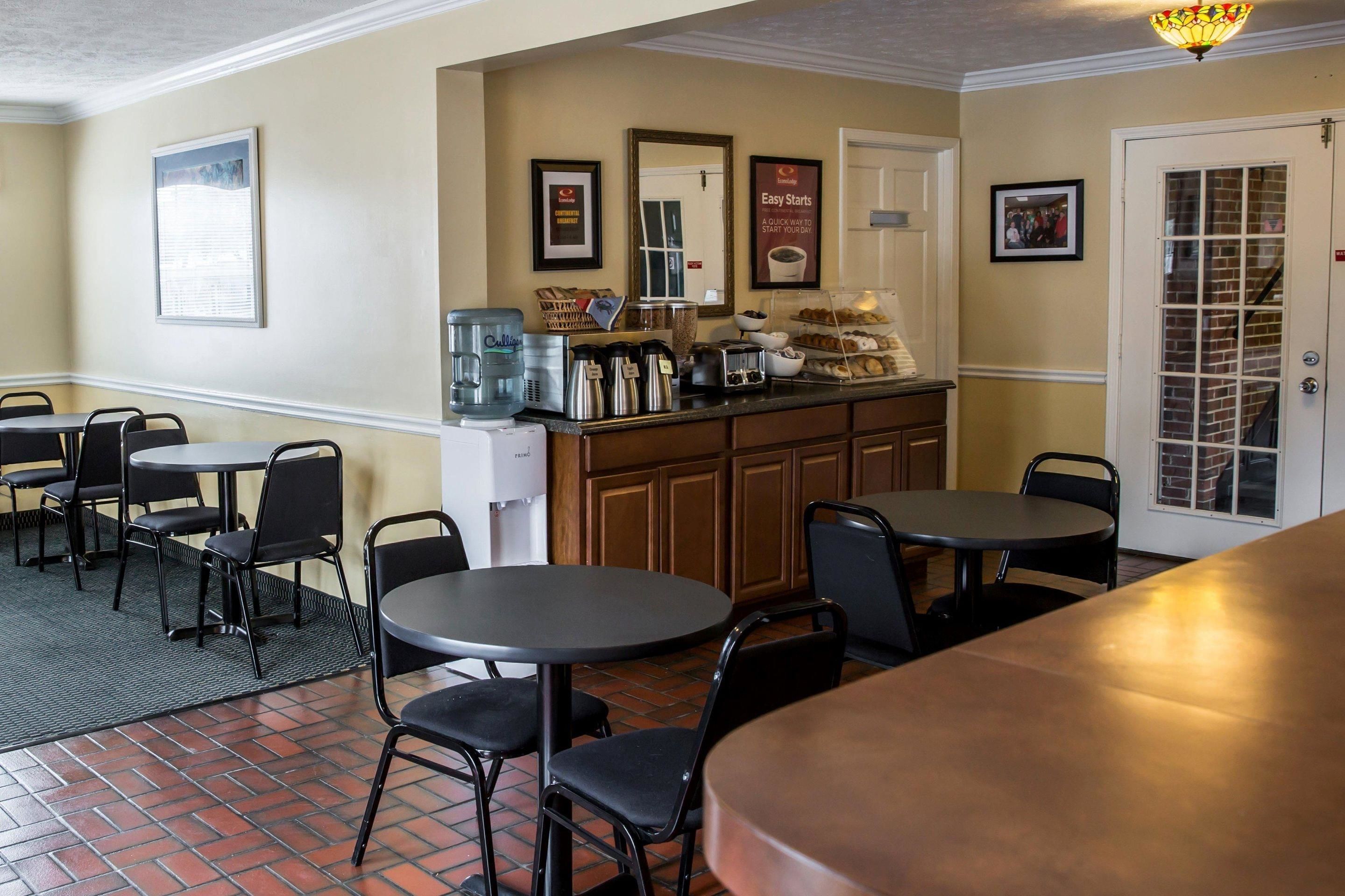 A restaurant with tables and chairs, a coffee station, and a door with a glass panel.