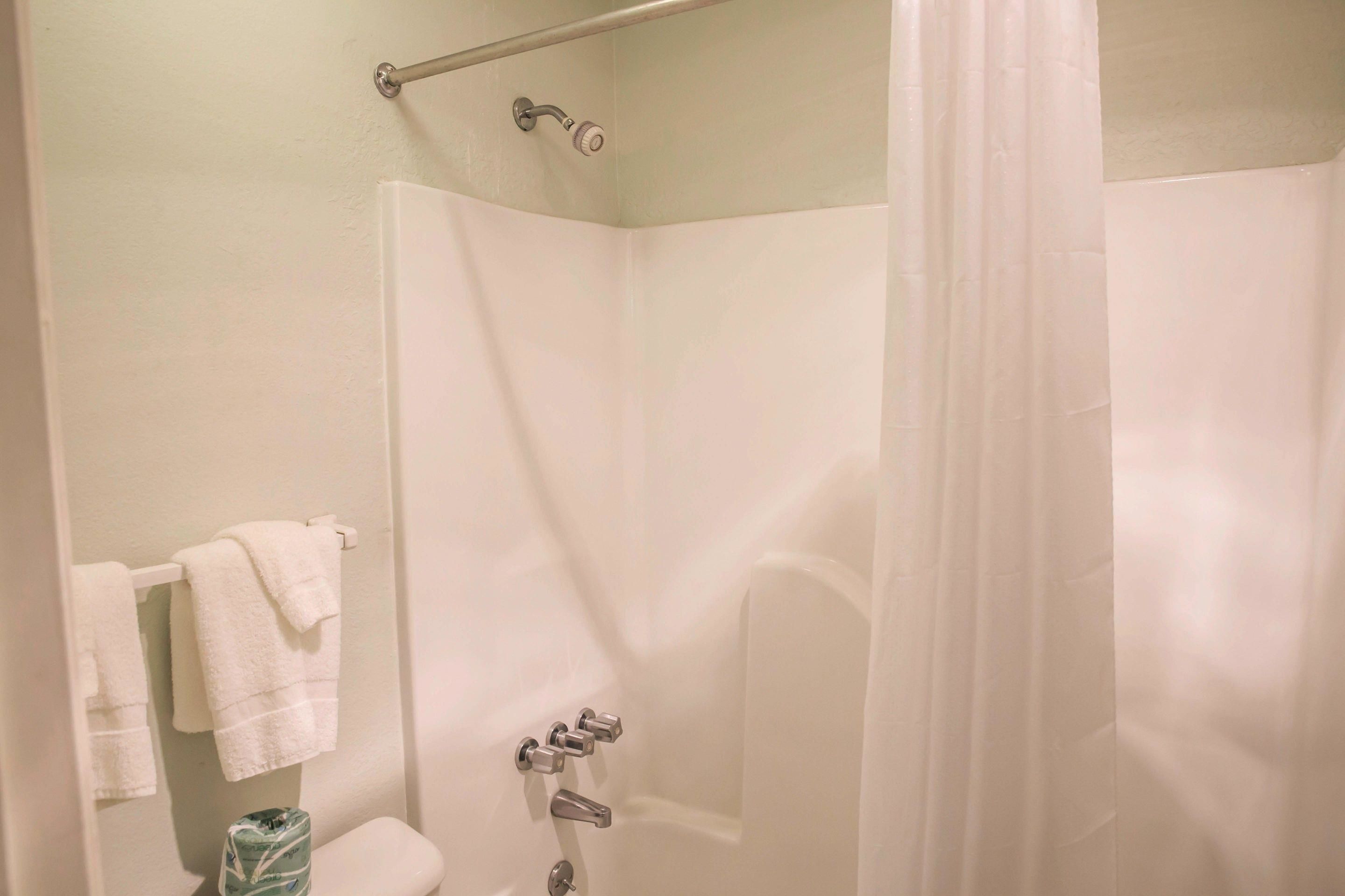 A shower with a glass door, a towel rack with two towels, and a toilet with a marble-like tile.