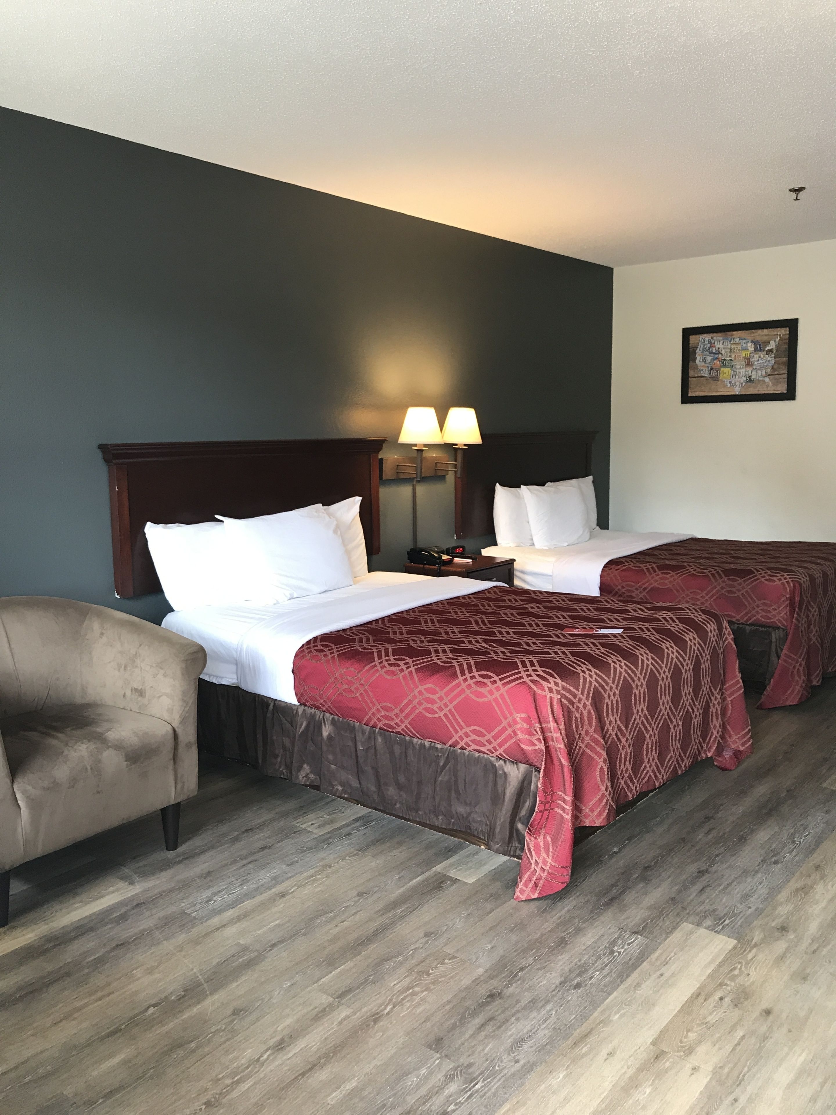 Habitació d'hotel amb dos llits, una cadira i una taula de nit amb làmpades.