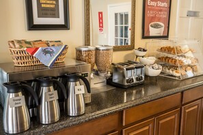 A breakfast buffet area with labeled coffee pots, a toaster, and a variety of pastries. - Econo Lodge Crystal Coast (Morehead City)