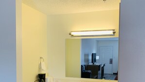 Un baño de hotel con un lavamanos blanco, espejo y suelo de madera.