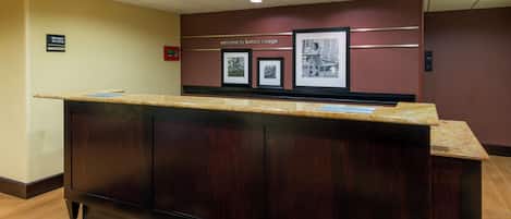 A reception desk with a dark wood finish, a marble top, and framed black and white photographs on the wall behind.