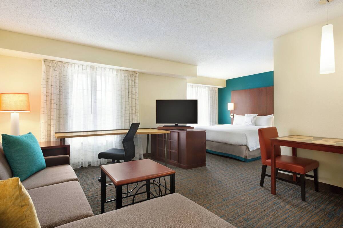 Een hotelkamer met een bed, een bureau met een televisie, een bank en een stoel.