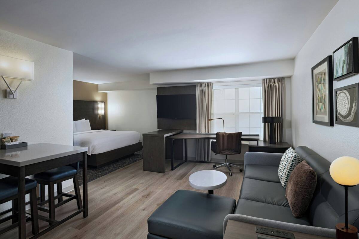 Een hotelkamer met een bed, bureau, sofa en een kleine tafel.