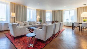 A modern living room with a sofa set, a coffee table, and a dining area with chairs. - Palace Hotel Tallinn, a member of Radisson Individuals (Tallinn)