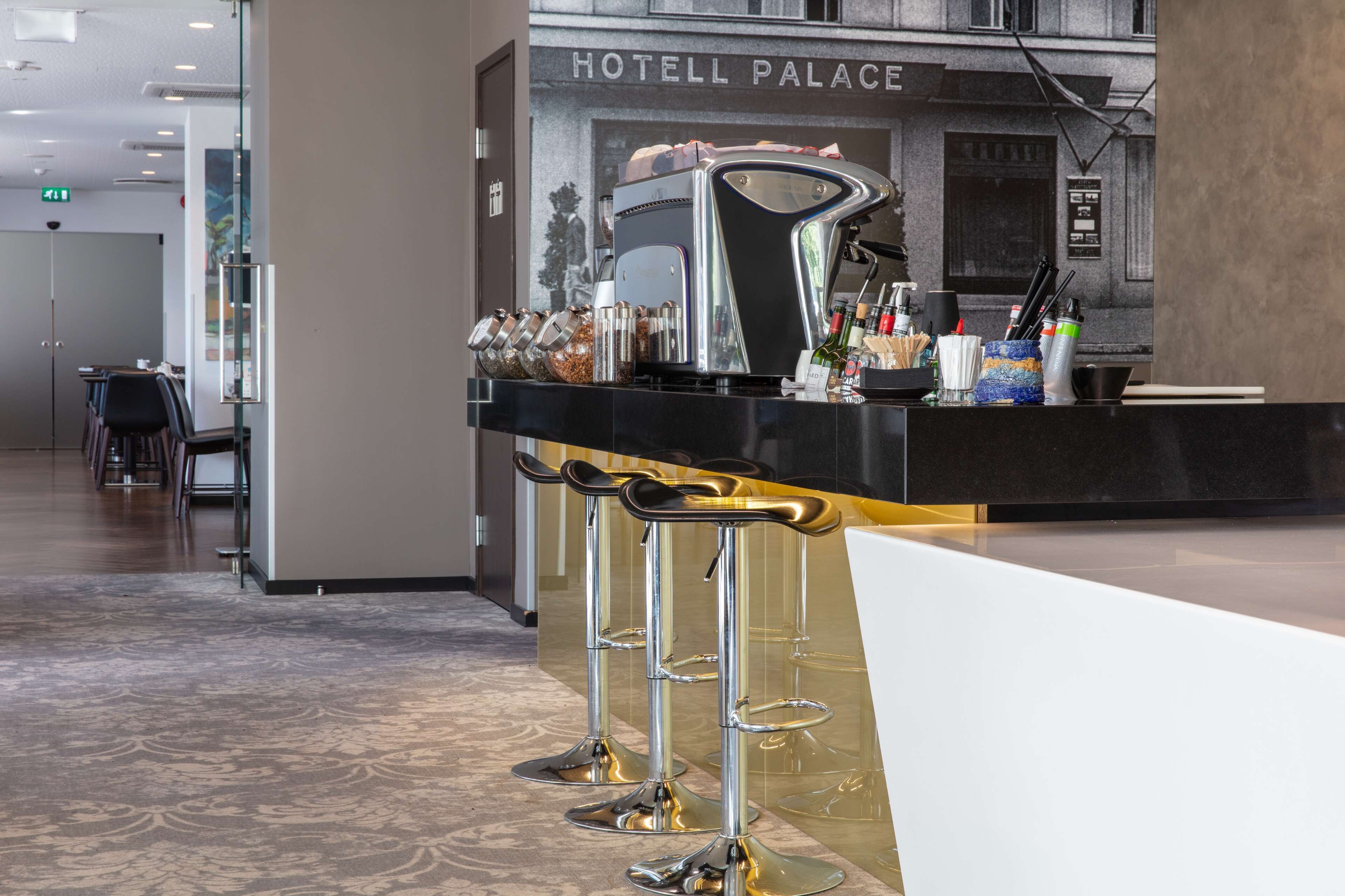 Un espace d’accueil d’hôtel doté d’un bar moderne et de coins salon.
