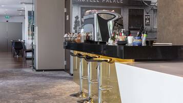 Un espace d’accueil d’hôtel doté d’un bar moderne et de coins salon.
