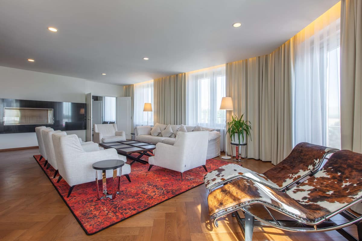 A modern living room with a sofa, chairs, a coffee table, and a red rug.