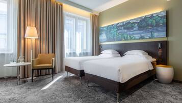 Een hotelkamer met een groot bed, een stoel, een kleine tafel en een schilderij aan de muur.