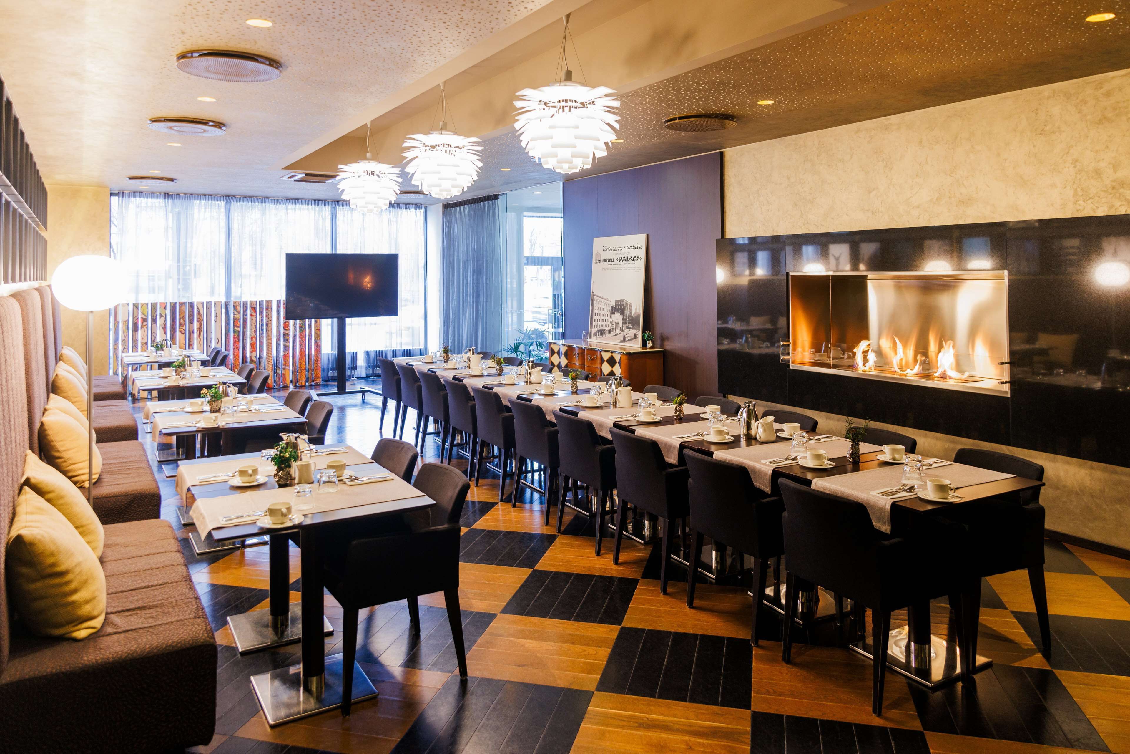 A restaurant with multiple tables, chairs, a fireplace, and a television.
