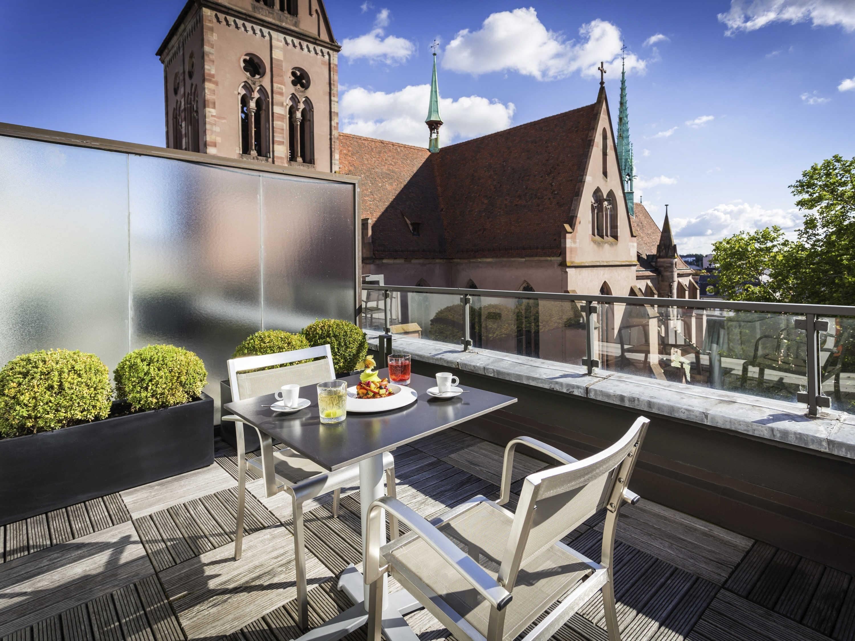 A terrace with a table and chairs, a view of a church, and a building with a clock tower.