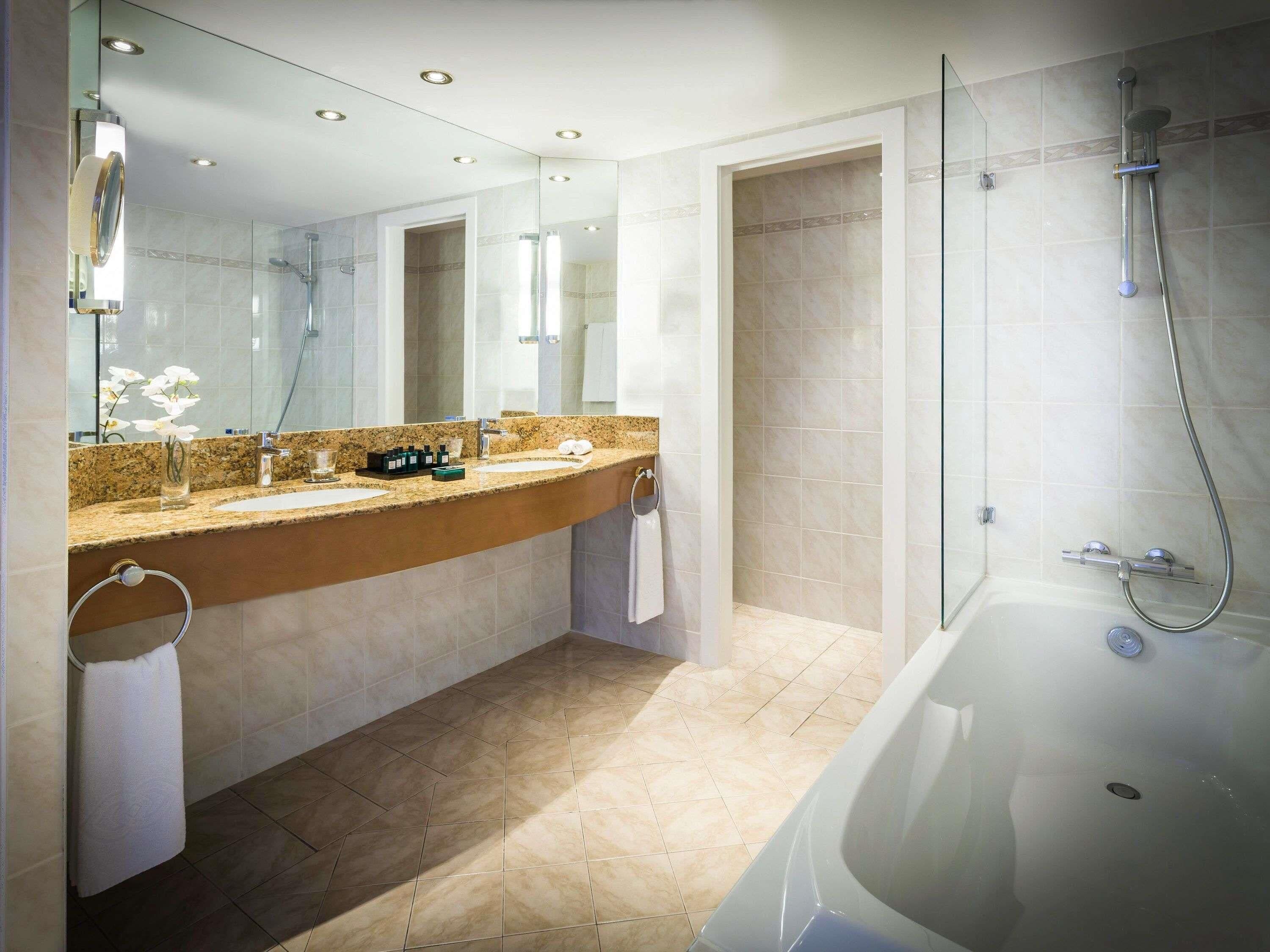 A modern bathroom with a large mirror, a bathtub, and a shower area.