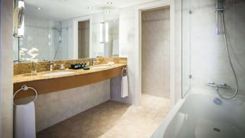 A modern bathroom with a large mirror, a bathtub, and a shower area.