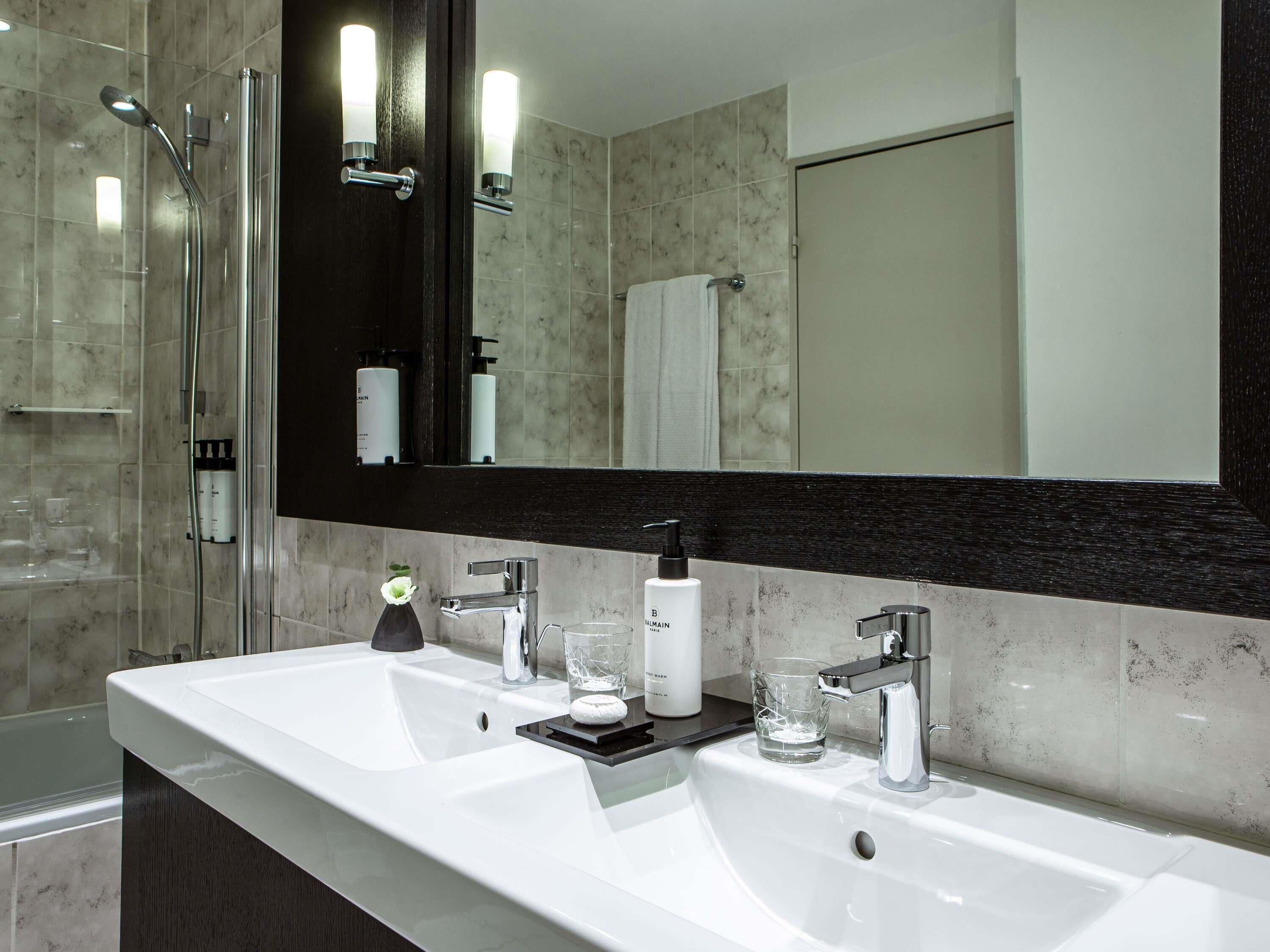 Une salle de bain moderne avec un double vasque, une douche à l’italienne en verre et un grand miroir.