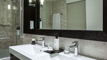 Une salle de bain moderne avec un double vasque, une douche à l’italienne en verre et un grand miroir.