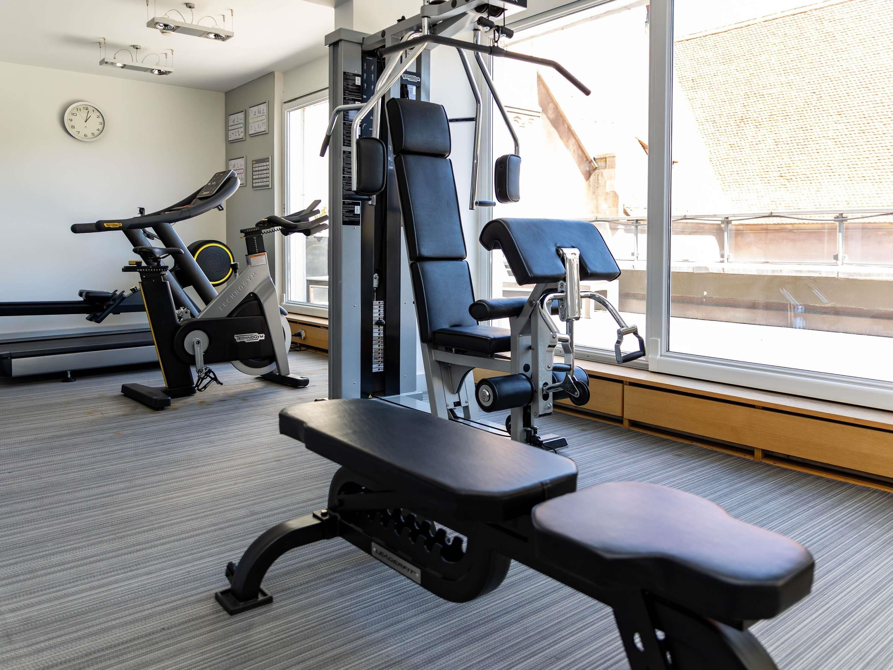 A gym with exercise equipment, a bench, and a large window with a view.
