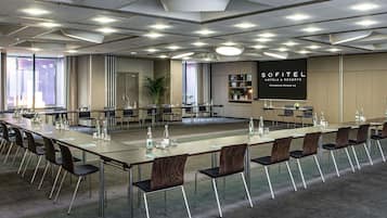 Une salle de conférence équipée d’une longue table, de chaises et d’un écran de projection affichant le logo « SOFITEL HOTELS & RESORTS ».
