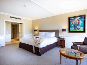 A hotel room with a large bed, bedside tables, a chair, a glass coffee table, and a painting on the wall. - Sofitel Strasbourg Grande Ile (Strasbourg)