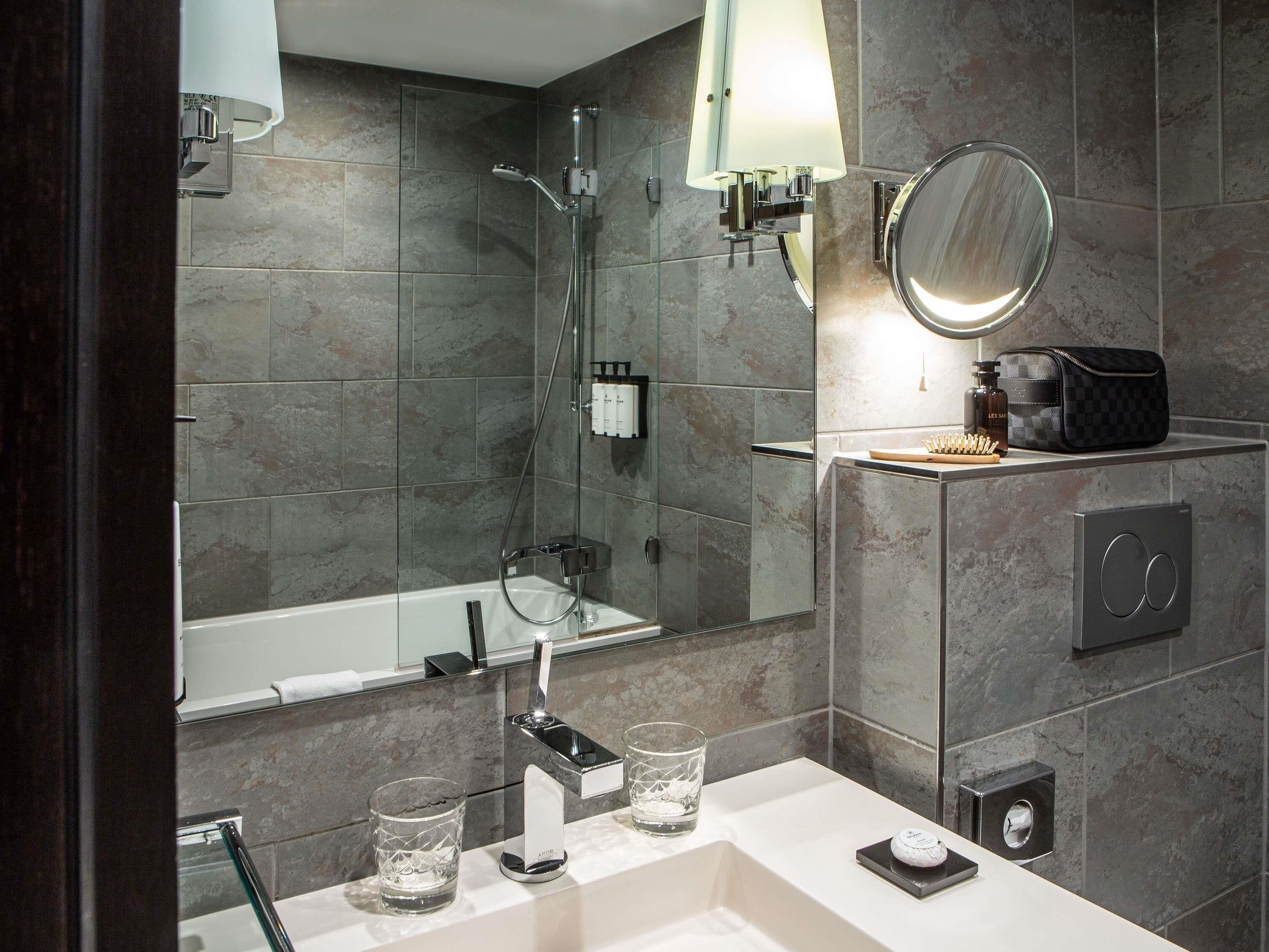 A modern bathroom with a bathtub, a shower, a vanity with a mirror, and toiletries.