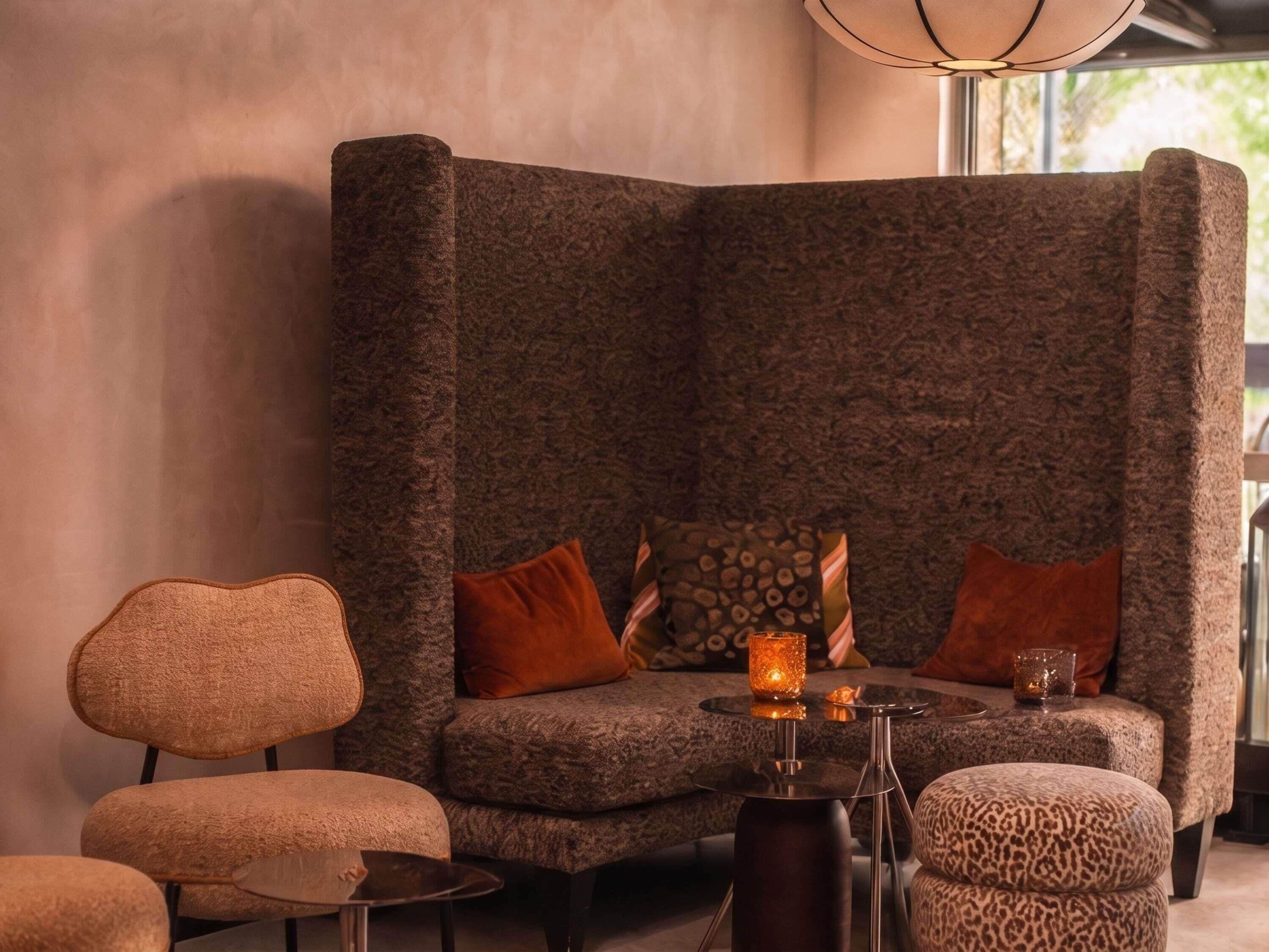 A modern living room with a textured sofa, a matching armchair, a small round table, and a leopard print ottoman.