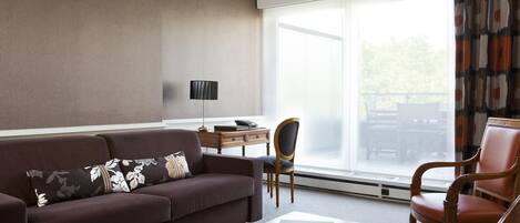 Una sala de estar moderna con un sofá marrón, una mesa de centro de madera y un escritorio con una lámpara.