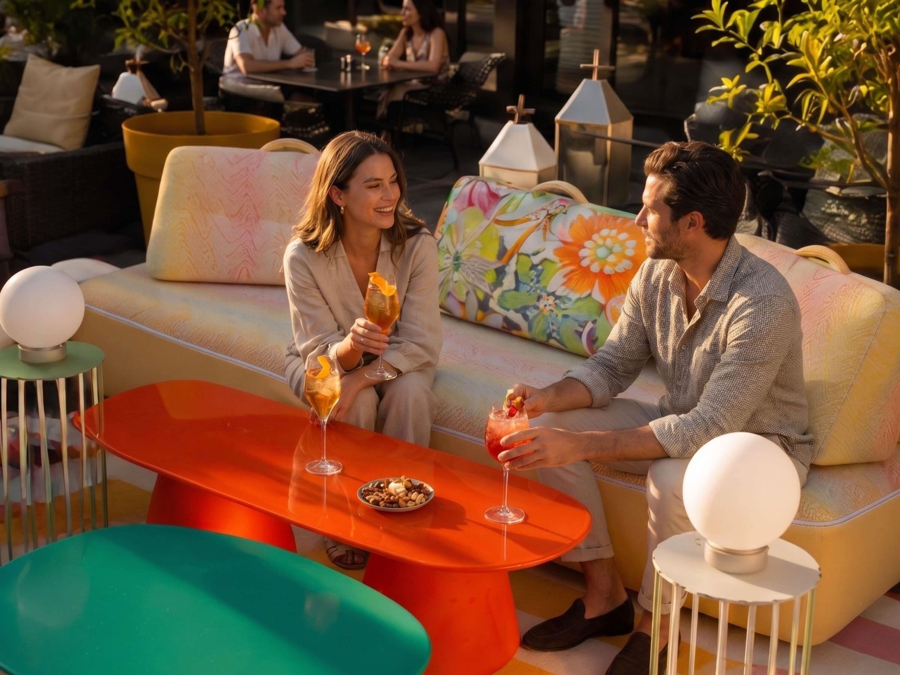 A couple seated on a sofa with a table between them, holding drinks.