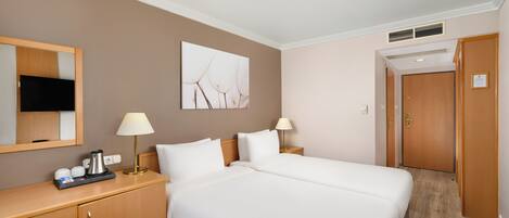 Une chambre d’hôtel avec un lit double, un bureau avec une lampe, une machine à café et un tableau au mur.